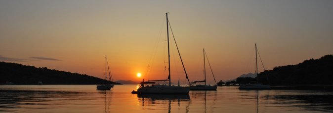The sun rises over the harbour at Paleo Epidauros silhouetting moored sailing yachts