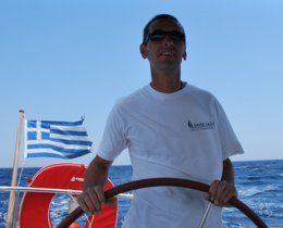 A Greek Sails skipper helms while the crew relax, enjoying their sailing holiday