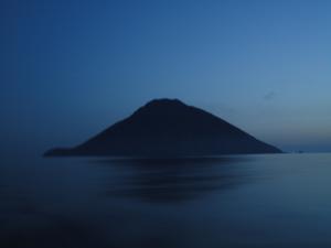 The volcano of Stromboli rises from the sea in the early morning light. The volcano erupts every 5-10 minutes spitting orange lava into the air and sending and orange river down to meet the sea