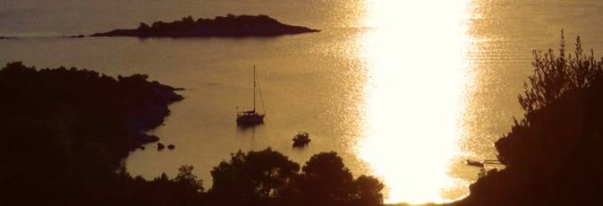 The sun sets as a yacht lies at anchor near our base in Poros, Greece